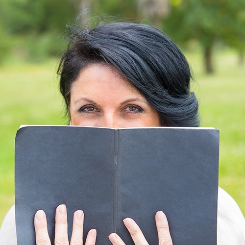 woman hiding behind book
