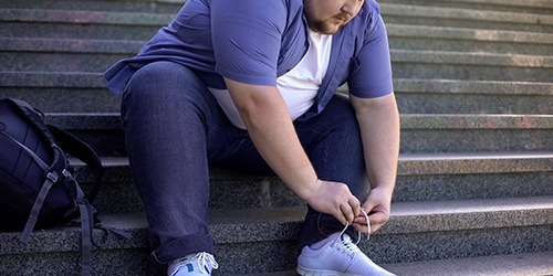 obese man tying shoe