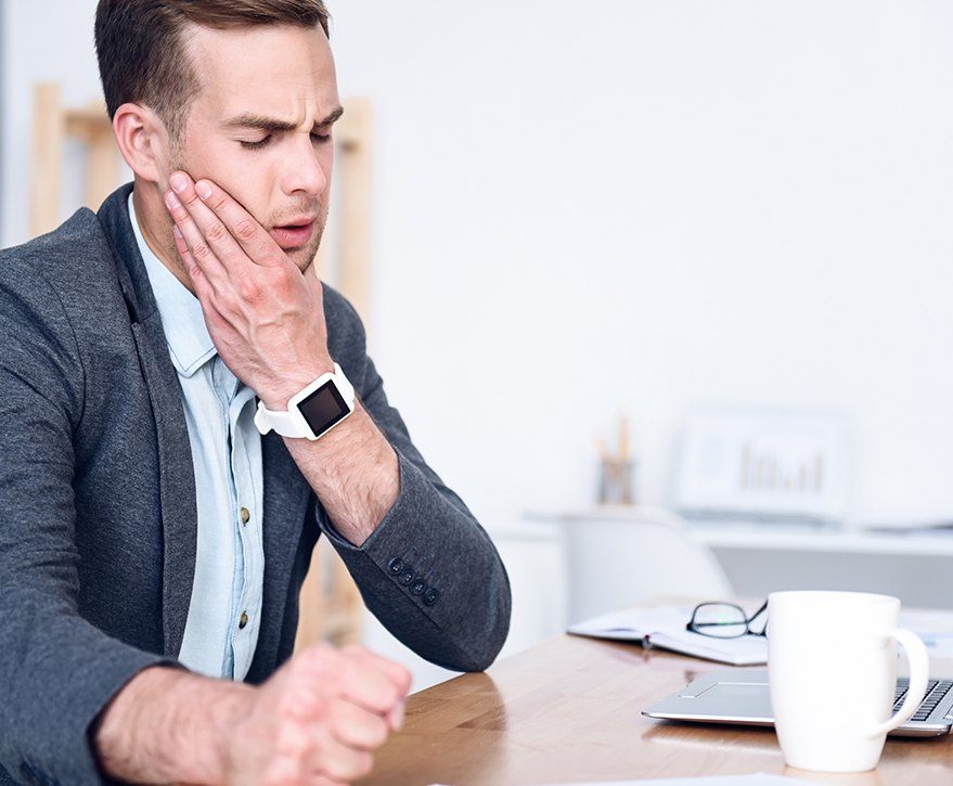 man in business attire holding jaw in pain