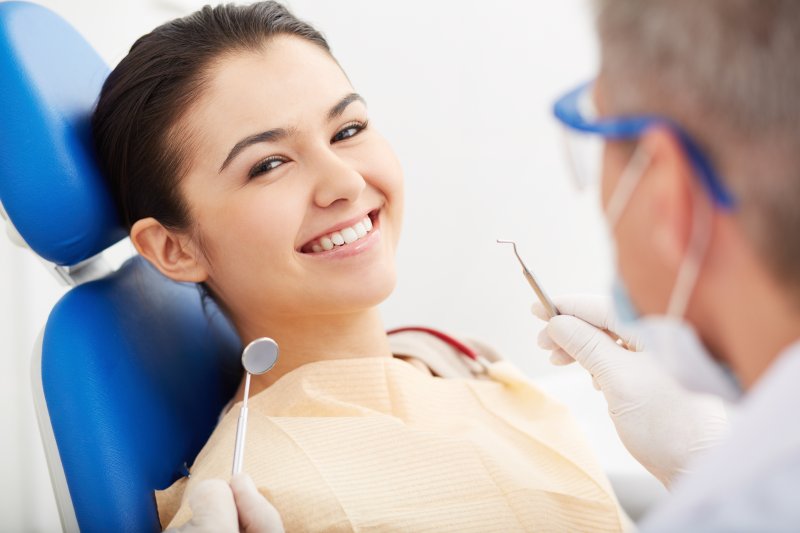 a young woman smiling while undergoing a dental checkup with her dentist
